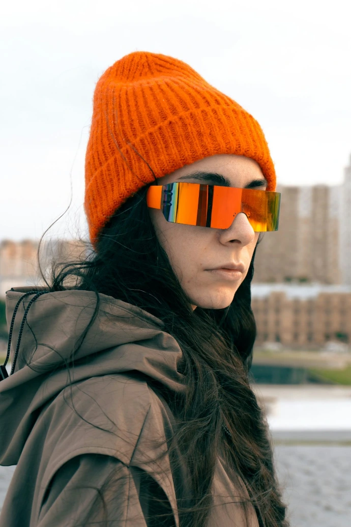 Woman wears sunglasses and an orange beanie.